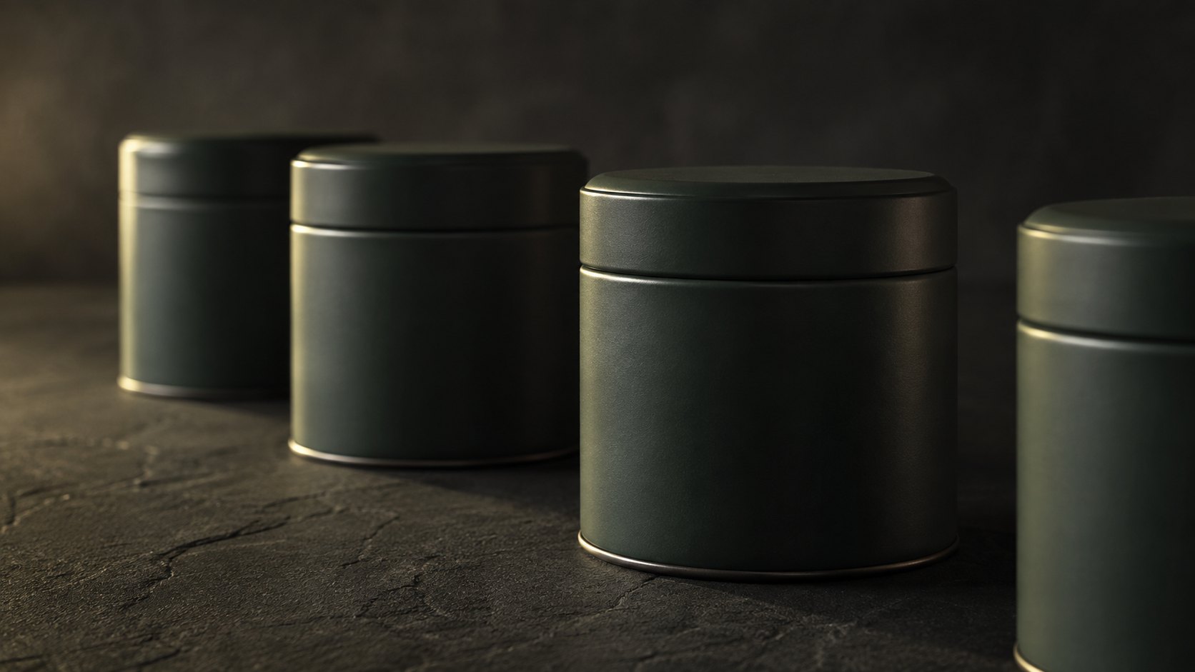 Matte deep green tea tins lined up on a black basalt surface